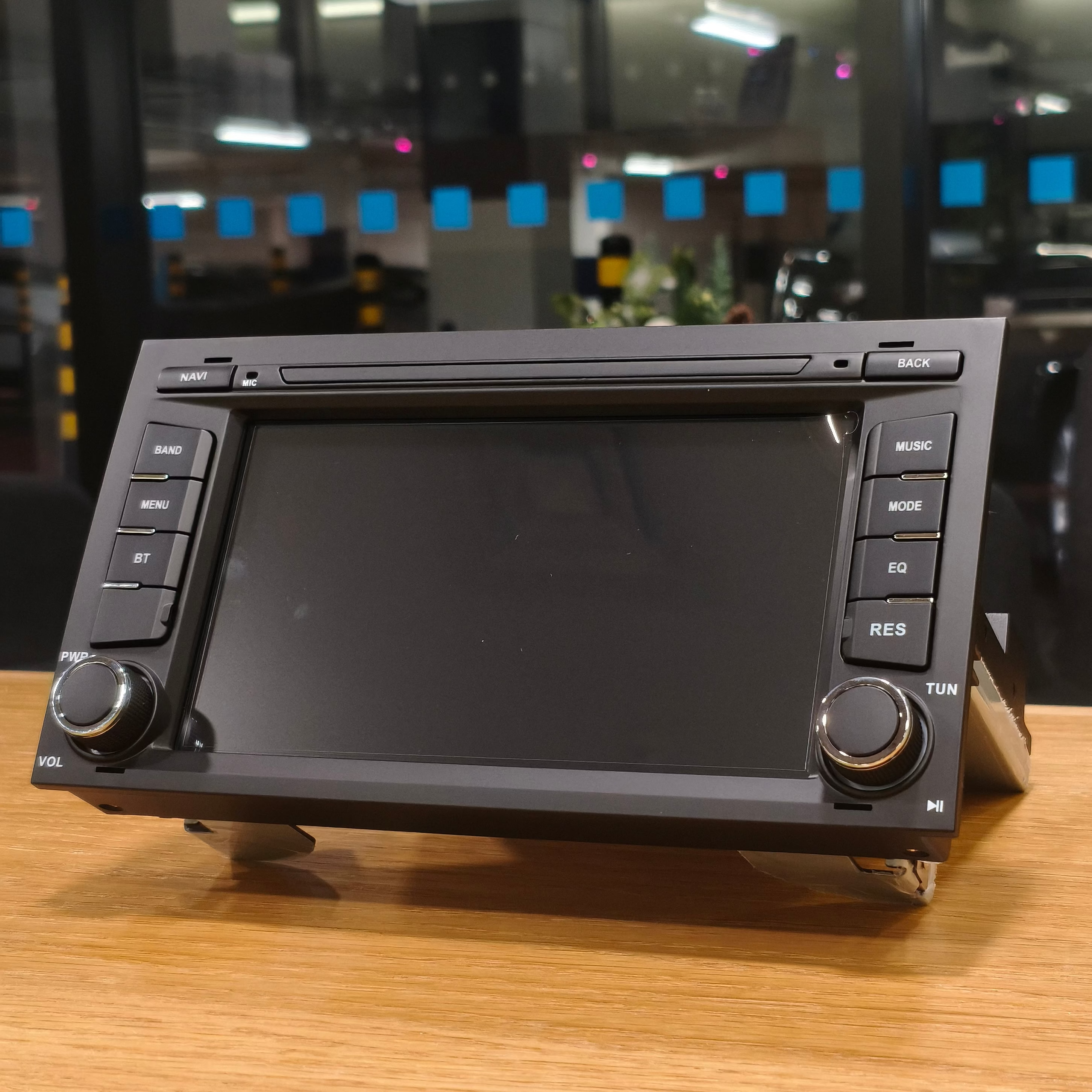 Car stereo system on a wooden surface with a blurred indoor background