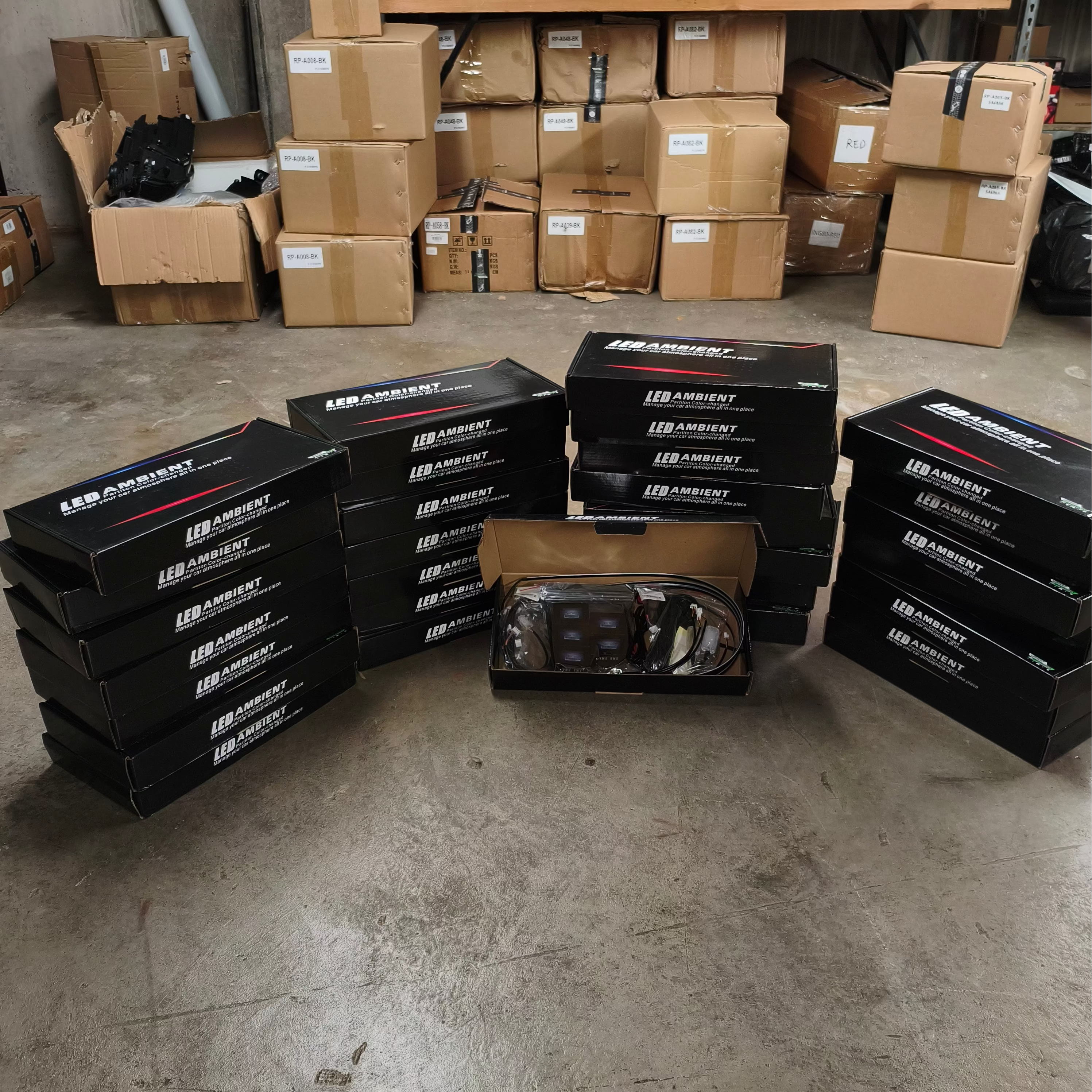 Stacks of ambeint lighting boxes with visible branding in a warehouse setting.